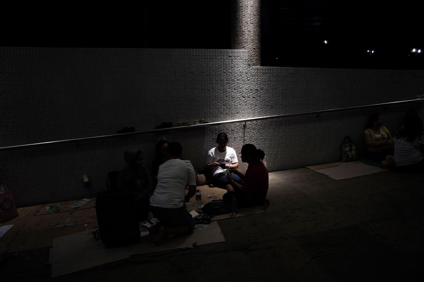 CHINA. Hong Kong, October 2012. Women have a sit in a pedestrian passage. Many immigrant workers from other asian countries gather and seat on sidewalks and public places to talk each other or to have lunch and dinner together.